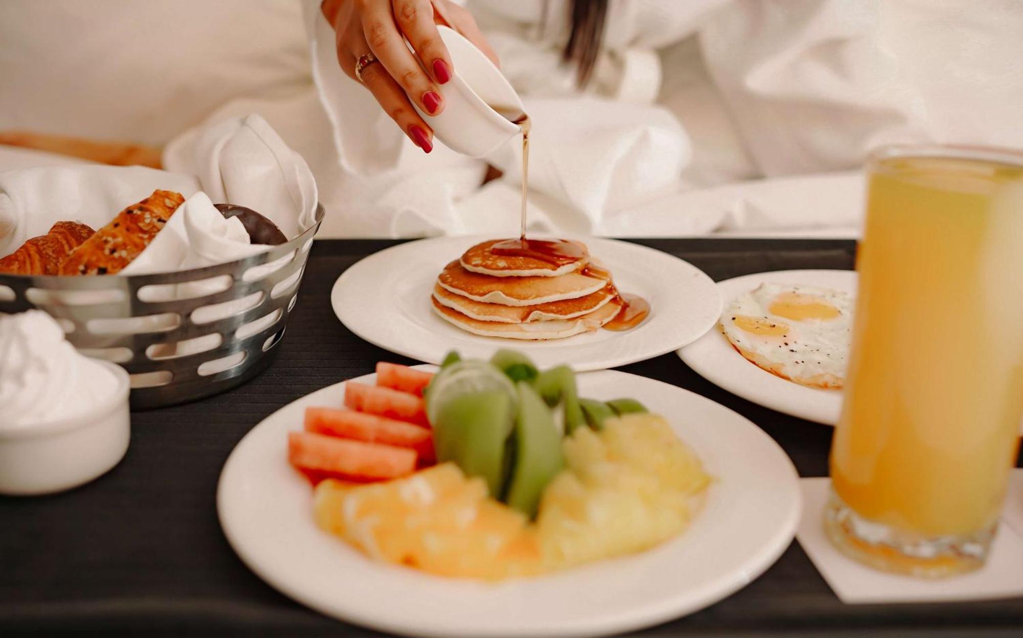 Radisson Blu Hotel Amritsar Zewnętrze zdjęcie A woman pouring maple syrup on a stack of pancakes